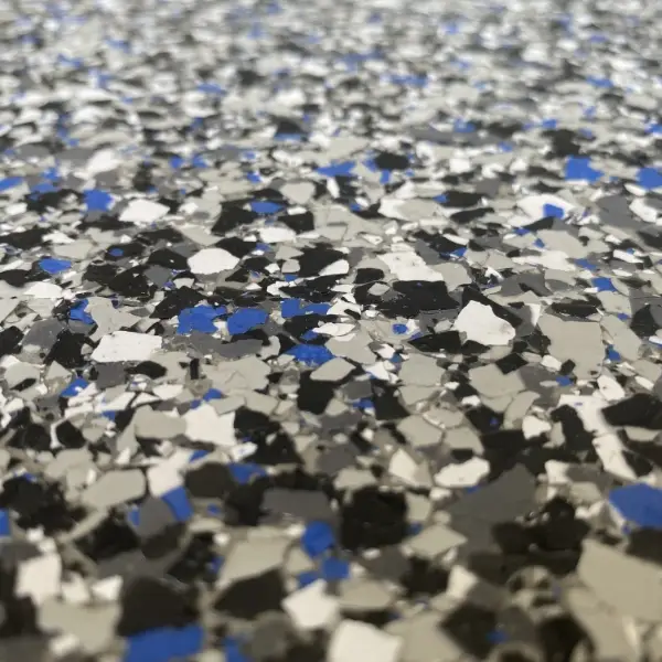 A close-up view of a speckled floor with black, white, gray, and blue paint chips, creating a textured pattern.